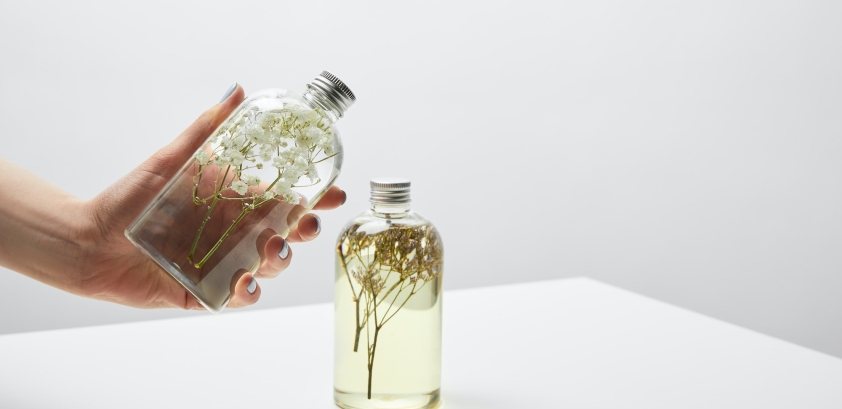 cropped view of woman holding bottle with organic shampoo on white table