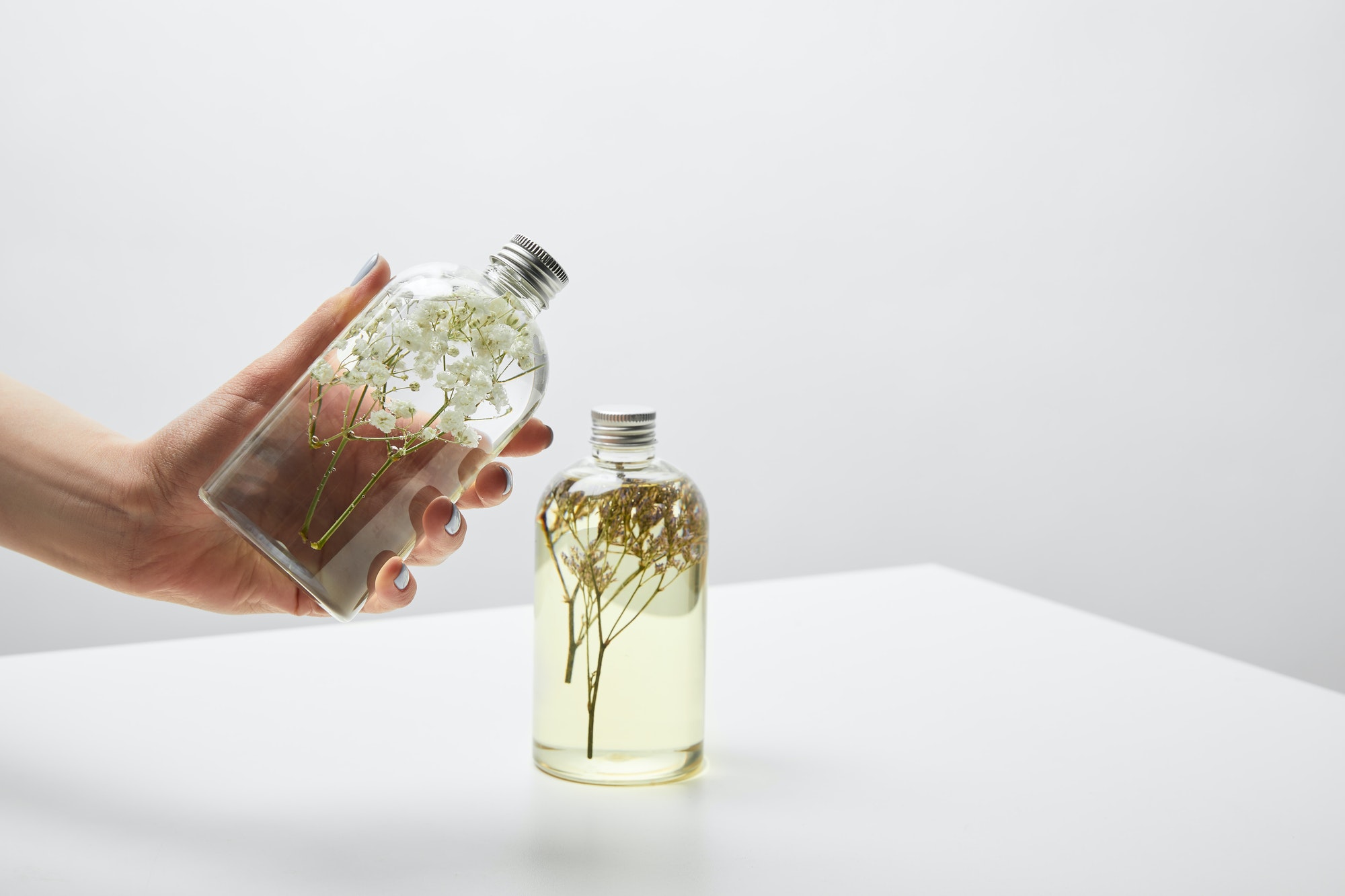 cropped view of woman holding bottle with organic shampoo on white table